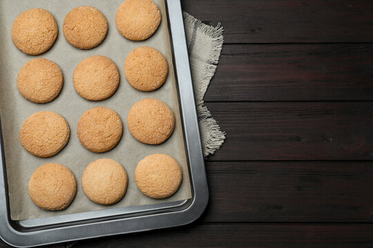 Baking sheet with delicious sugar cookies on wooden table, top view. Space for text