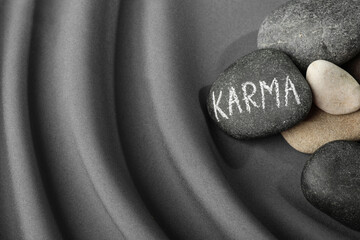 Stones with word Karma on grey fabric, above view. Space for text