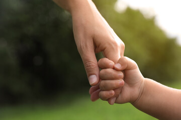 Daughter holding mother's hand in park, closeup. Happy family
