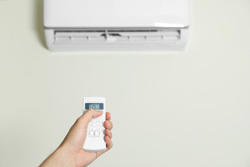 Fototapeta premium Man operating air conditioner with remote control indoors, closeup