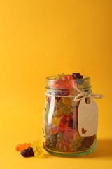 Delicious gummy bear candies on yellow background