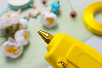 Hot glue gun over table with handicraft materials, closeup