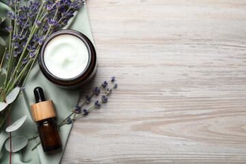 Jar of hand cream, lavender flowers and cosmetic product on white wooden, flat lay. Space for text