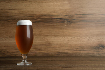 Glass of tasty beer on wooden table. Space for text