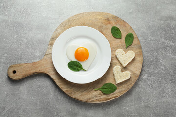 Romantic breakfast with heart shaped fried egg served on light grey table, top view
