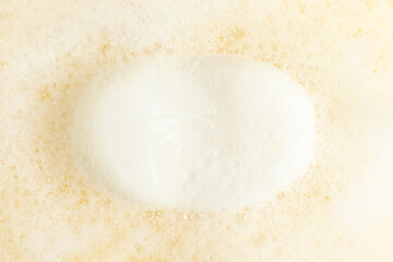 White soap and foam on yellow background. Top view.
