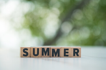 Wooden letters summer on table and against nature background. The concept of a summer.