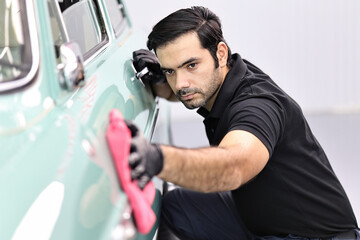 Car detailing - the man holds the microfiber in hand and polishes the car.