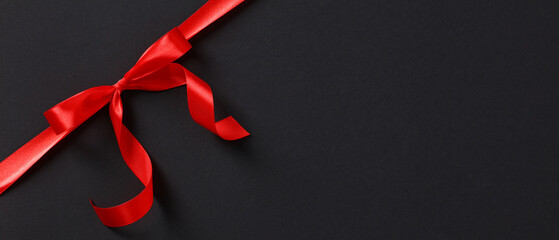 Red ribbon bow in corner on black background. Black Friday sale banner template.