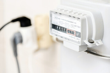 A gas meter,plug,electrical socket in the house, counter for distribution domestic gas. Symbolic image of a payment for heating,electricity in winter.Selective focus.