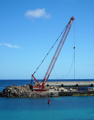 Fototapeta premium Crane placing large blocks to construct harbour wall.