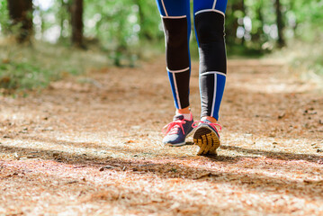 Fototapeta na wymiar Female runner jogging forward outdoors through a summer forest trail.Close up.Copy space.