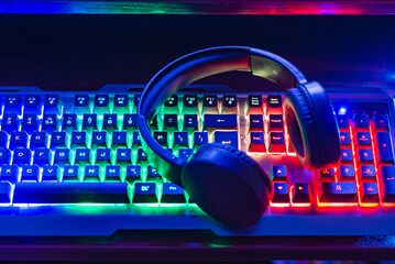 Pro gaming illuminated desk, headset, keyboard, computer neon lights. Cyber sport equipment laying on desktop, ready for online video gaming.Dark shot.