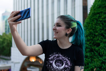 Beautiful young woman with blue hair selfie in the park
 - obrazy, fototapety, plakaty