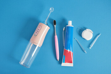 various dentifrices on a blue background, a set of teeth cleaning, dental floss, brush, irrigator,...