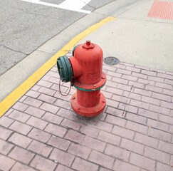 Fototapeta na wymiar A red fire hydrant on a brick sidewalk in Royal Oak, Michigan