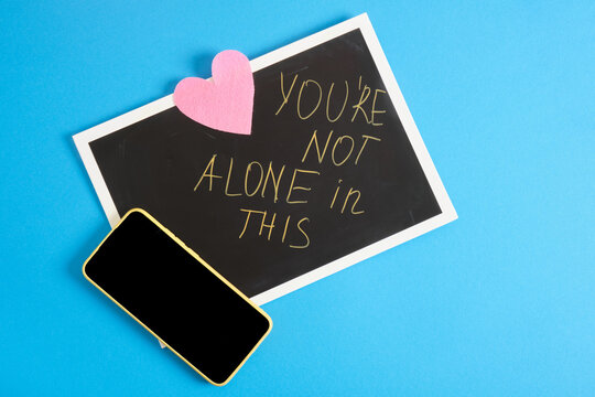 a smartphone and inscription for motivation on black cardboard, blue background, support service concept, call for help