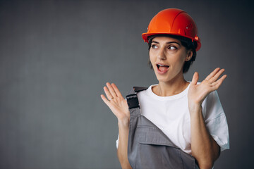 Woman builder in helmet wearing grey overalls