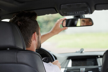 man adjusting the rearview mirror in his car