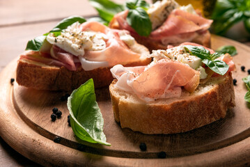 Deliziosi crostini conditi con prosciutto crudo, mozzarella e olio di oliva, cibo italiano 