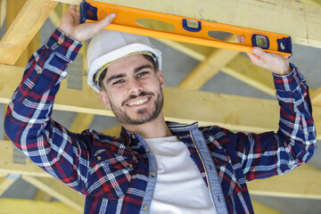 male construction worker using spirit level on wooden beam