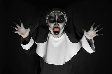 Scary devilish nun frightening on black background. Halloween party look