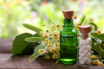Tincture, bottle of homeopathic remedy and linden flowers on wooden table, space for text