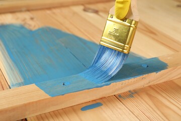 Worker applying blue paint onto wooden surface, closeup. Space for text