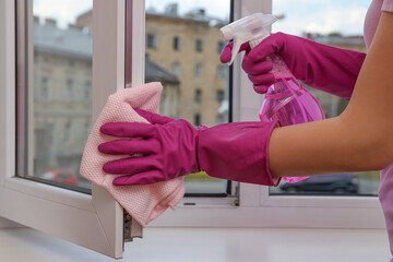 Young woman cleaning window frame with rag and detergent at home, closeup