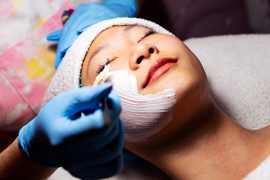 young asian woman receiving a moisturizing facial treatment, beauty and wellness concept