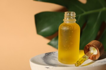 Bottle of face serum on soap dish against beige background, closeup. Space for text