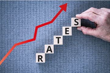 Rates on blue graph background with red arrow pointing upwards and hand completing the word Rates