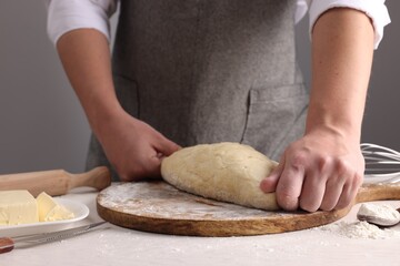 Man kneading dough at table near grey wall, closeup