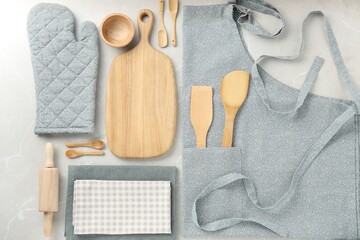 Fototapeta na wymiar Kitchen napkins, apron and different utensils on light grey table, flat lay