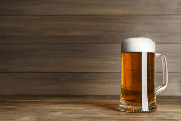 Mug of tasty beer on wooden table. Space for text
