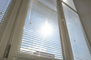 Obraz premium Stylish window with horizontal blinds in room, low angle view