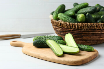 Whole and cut fresh ripe cucumbers on white table