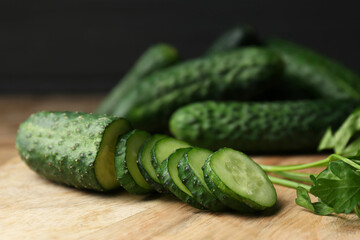 Fresh ripe cucumbers and parsley on wooden table, closeup