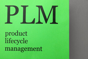 Green paper with abbreviation PLM (Product Lifecycle Management) on grey background, top view