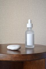 Transparent glass bottle with stone on wood. Cosmetic product package design. Empty label.