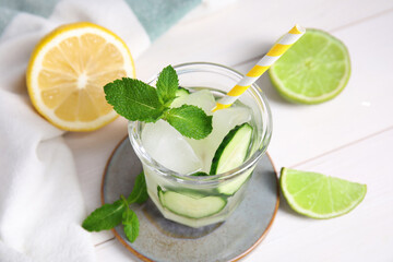 Glass of refreshing cucumber water with mint on white wooden table