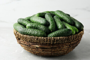Fresh ripe cucumbers in wicker basket on marble table