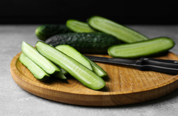 Whole and cut fresh ripe cucumbers on grey table