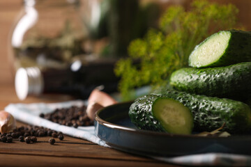 Fresh cucumbers and other ingredients prepared for canning on wooden table, closeup. Space for text