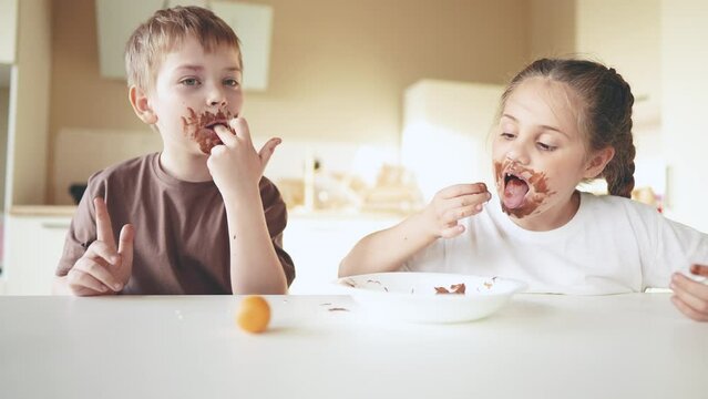 baby boy and girl eat lifestyle chocolate. dirty little baby kids in the kitchen eating chocolate in the morning. happy family eating sweets kid dream concept. baby dirty face eating chocolate cocoa