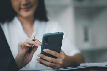 Woman gesturing and looking at the mobile phone, business woman checking company monthly sales and pretending to be happy as sales meet planned targets according to policy. Sales management concept.