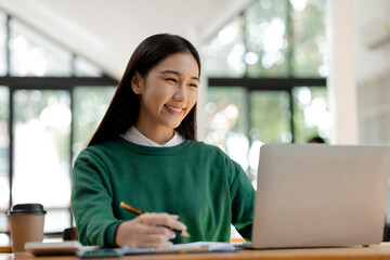 Asian woman working on laptop, female employee of a marketing company, she is working on a...