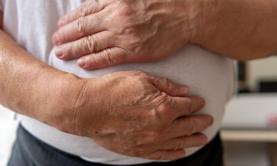 A person holding the stomach suffering from stomach pain.