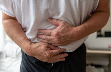 A person holding the stomach suffering from stomach pain.