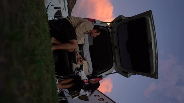 VERTICAL of van life couple having dinner under the sunset while camping in outdoor natural spot travelling in van